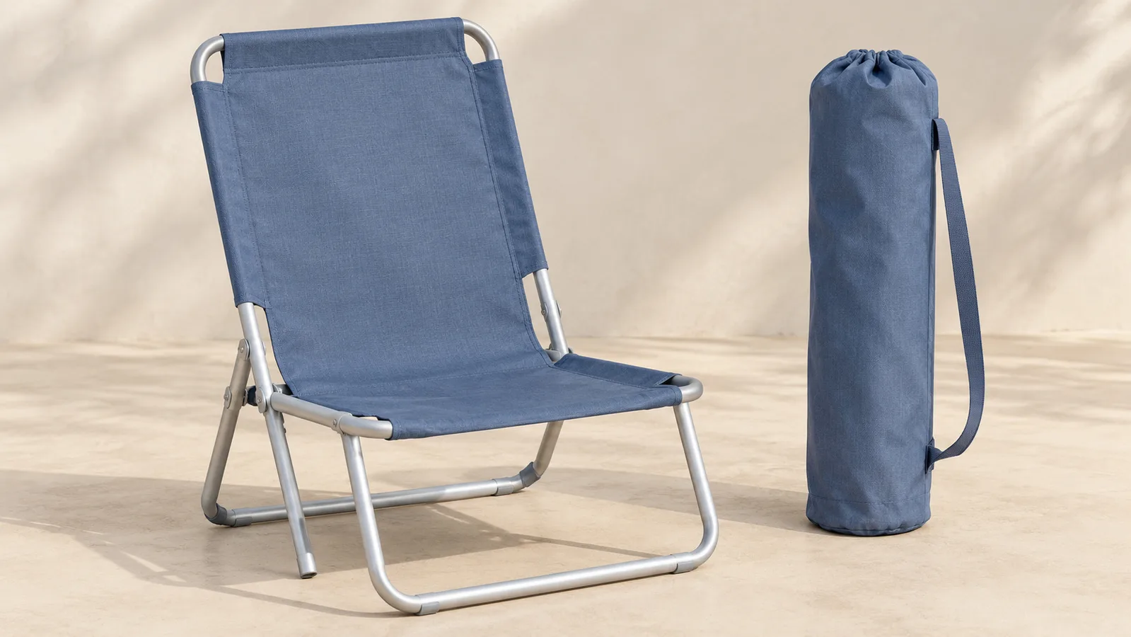 Een eenvoudige opvouwbare strandstoel, open afgebeeld naast de bijpassende draagtas